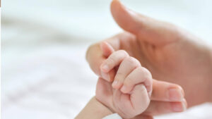 Mano de bebé sujetando el dedo de la mano de su mamá