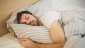 Hombre durmiendo, abrazando la almohada ezn la cama
