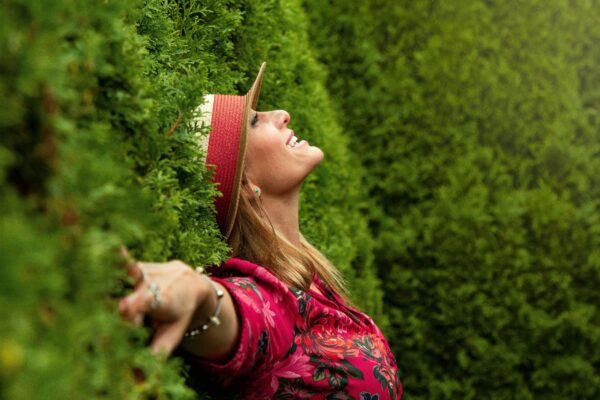 Mujer sonriendo recostada en un arbusto