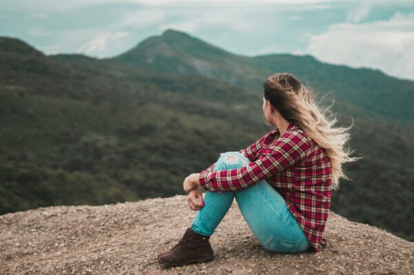 Mujer sentada con las piernas recogidas mirando a las montañas