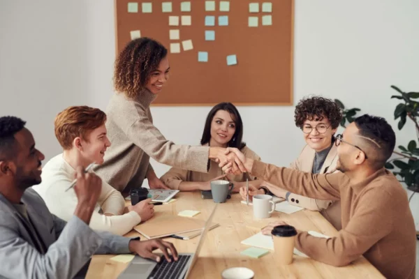 Grupo de personas reunidas , dos de ellas tomándose de las manos.