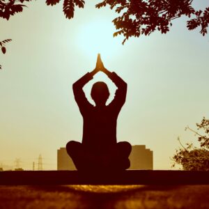 Mujer meditando en el parque con atardecer.